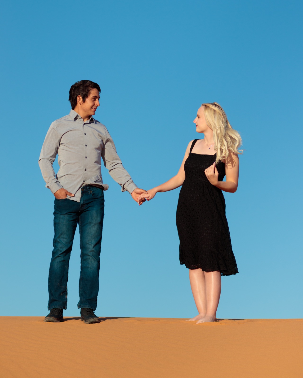 A couple holding hands beneath a clear blue sky