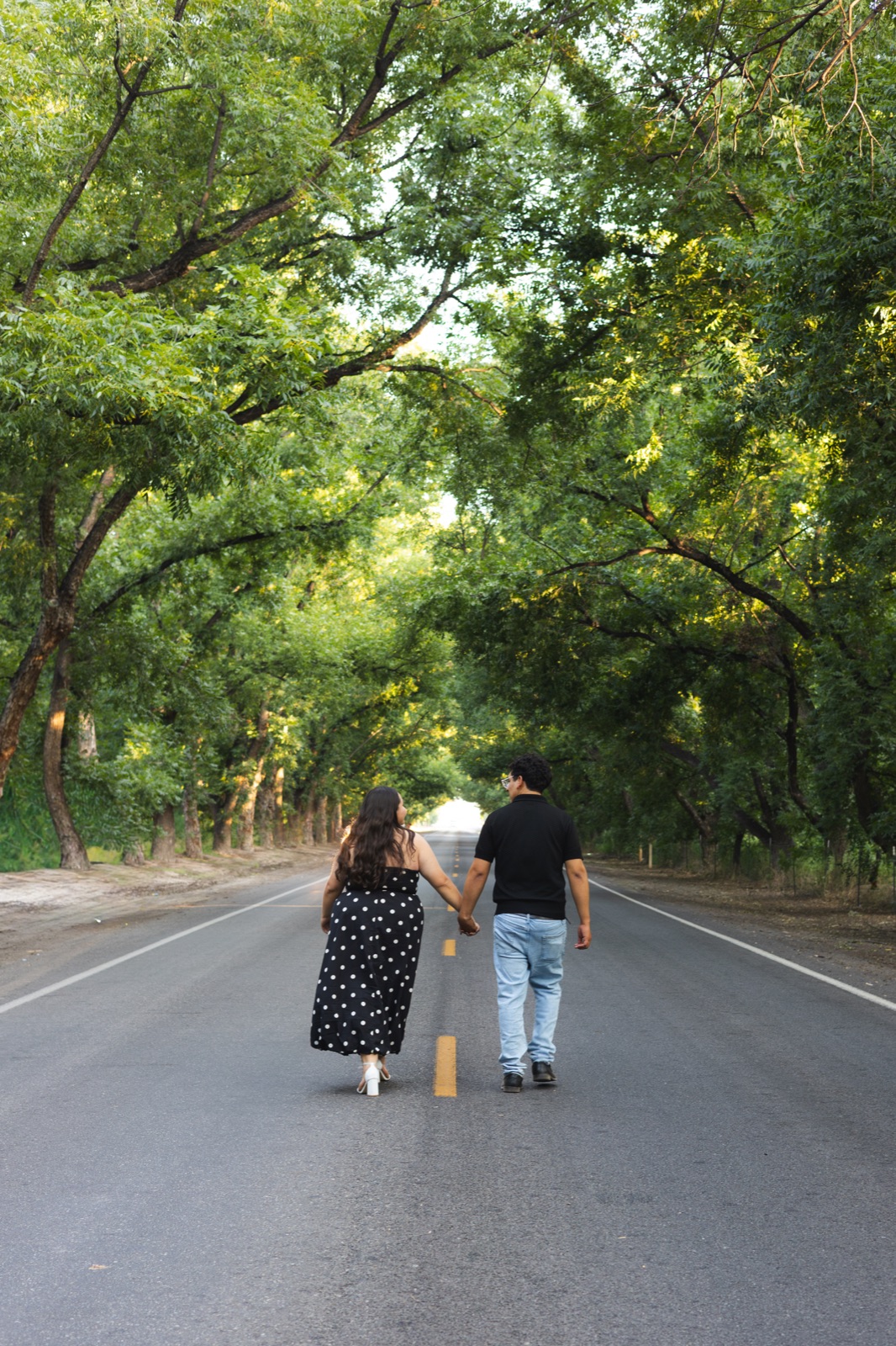 A couple walking beneath green trees