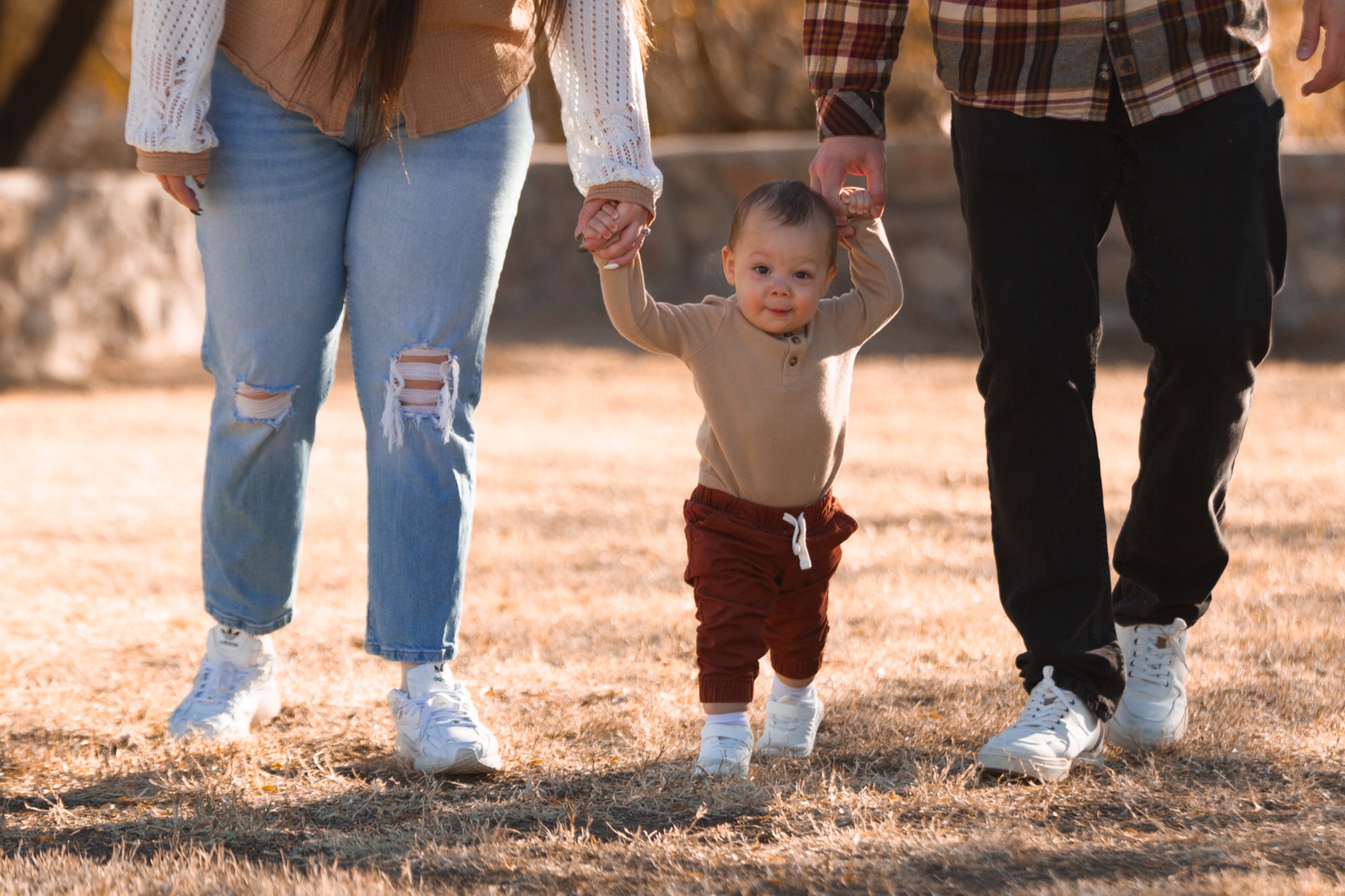 A toddler walking between parents