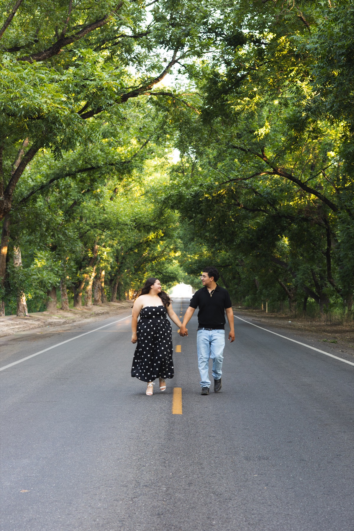 Daisy and Andy walking hand in hand along a tree-lined road