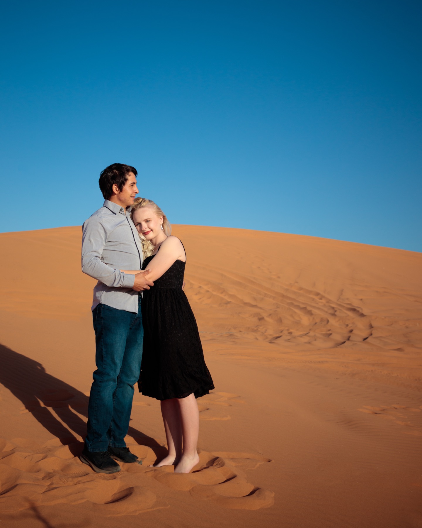 Desirae and Jorge embracing in a sunlit desert landscape