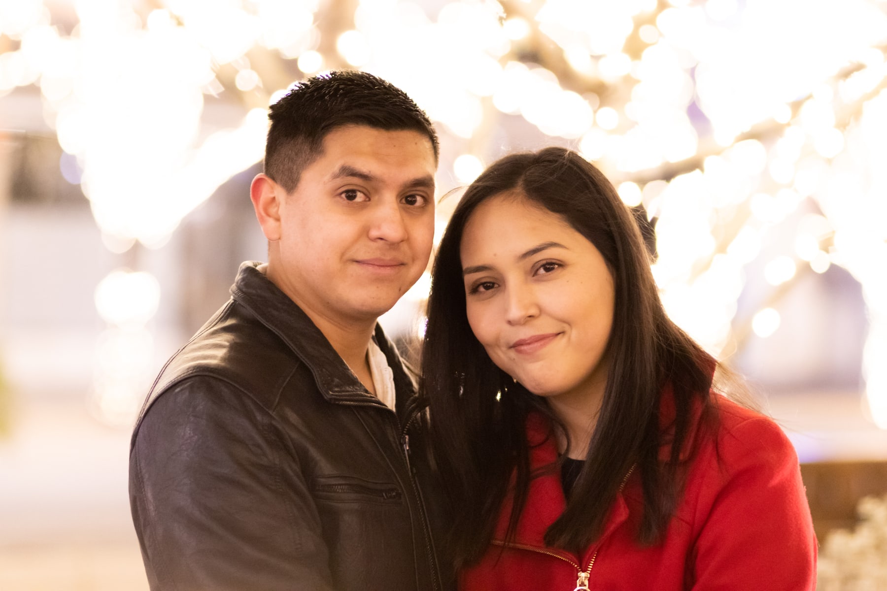 A couple close together beneath warm white lights