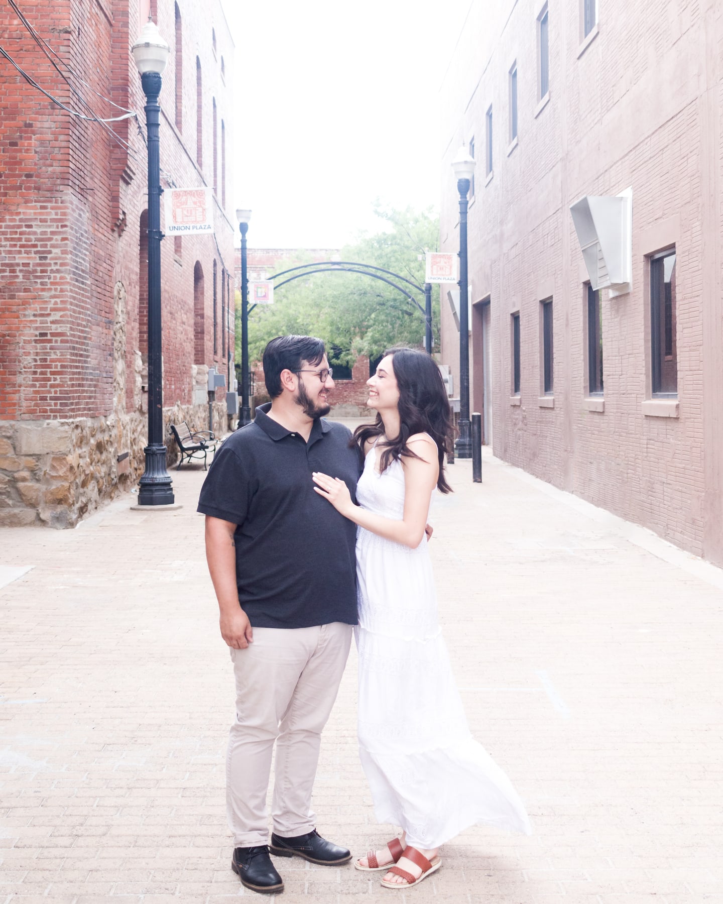 A couple smiling at each other in a brick-lined alley