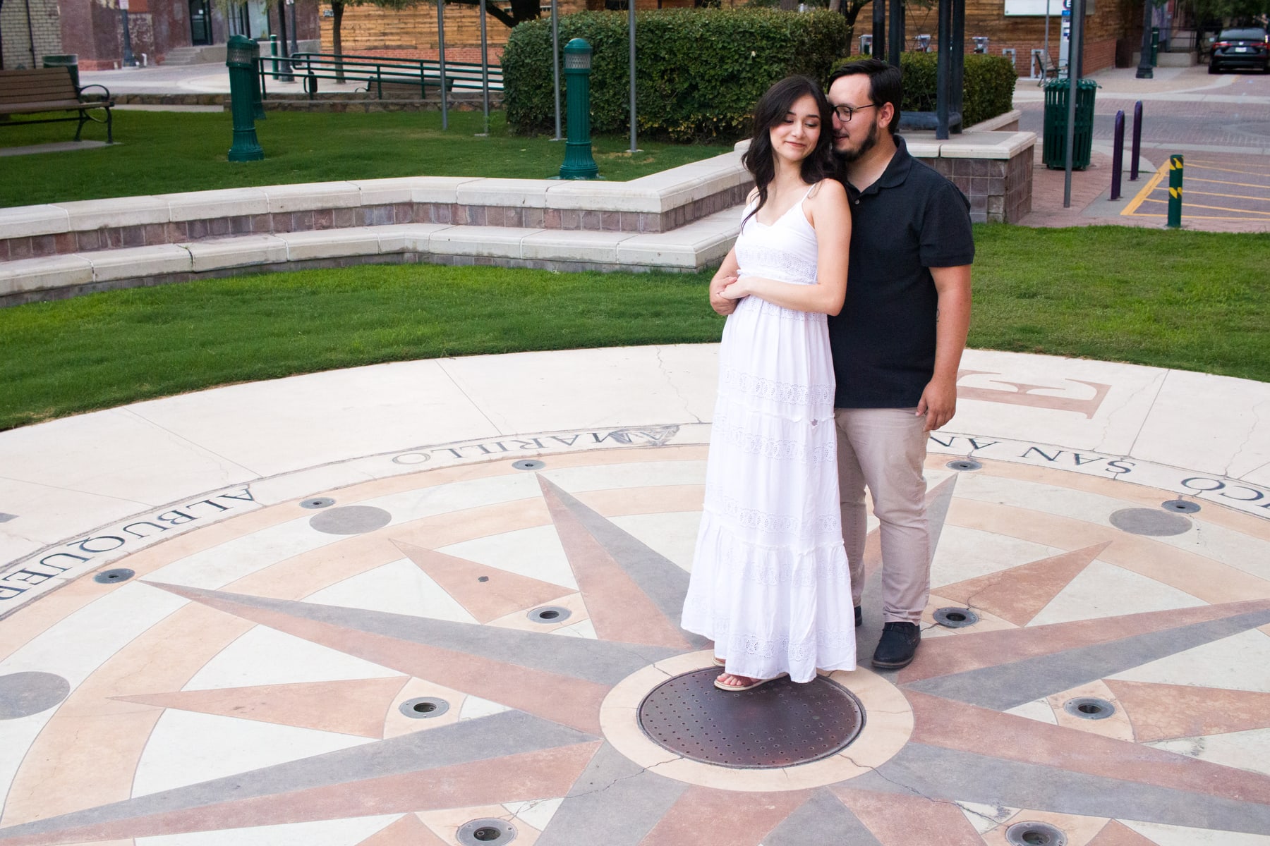 A couple standing together on a compass design in an outdoor plaza