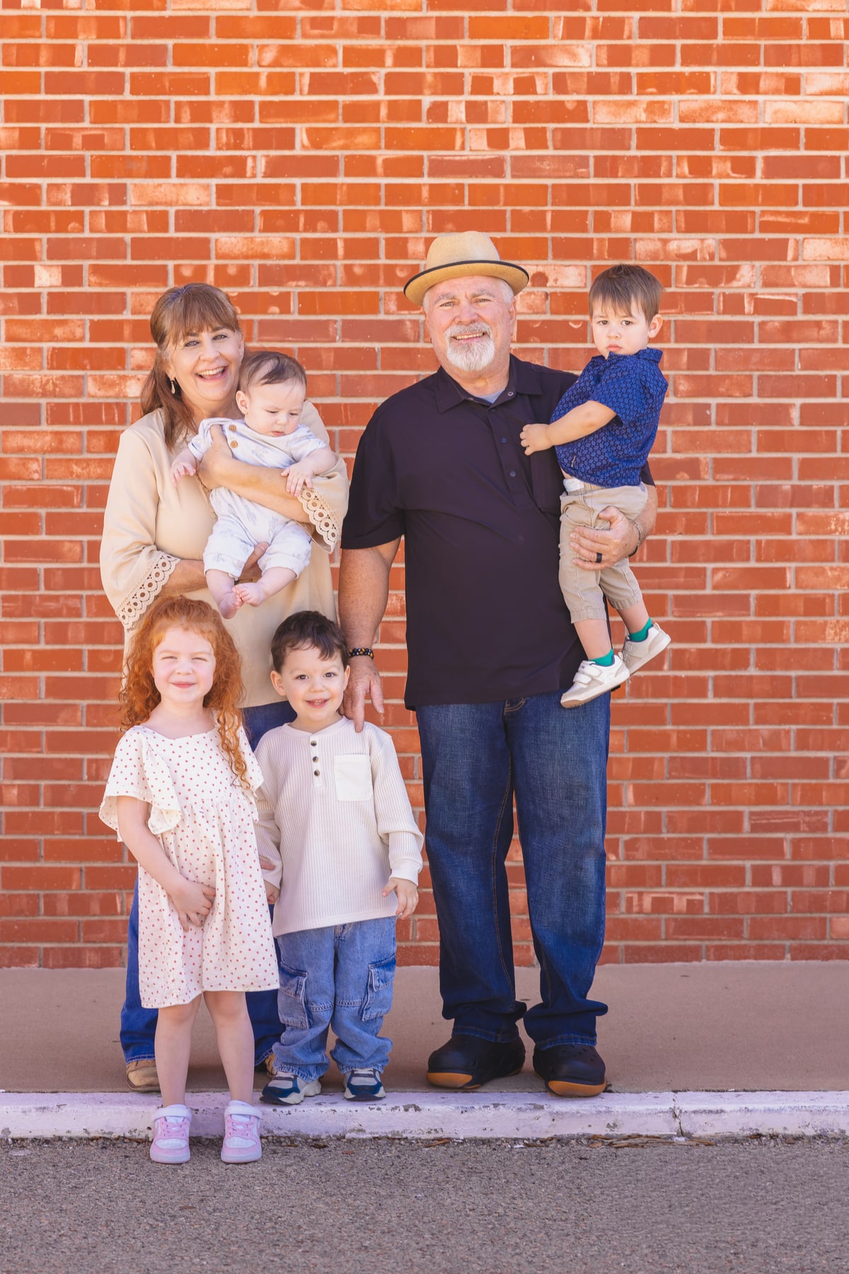 Two adults posing with four children in front of a brick wall