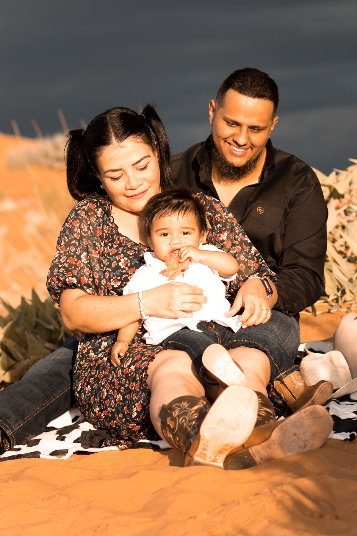 Ruby and Misael sitting together with their baby in a golden field