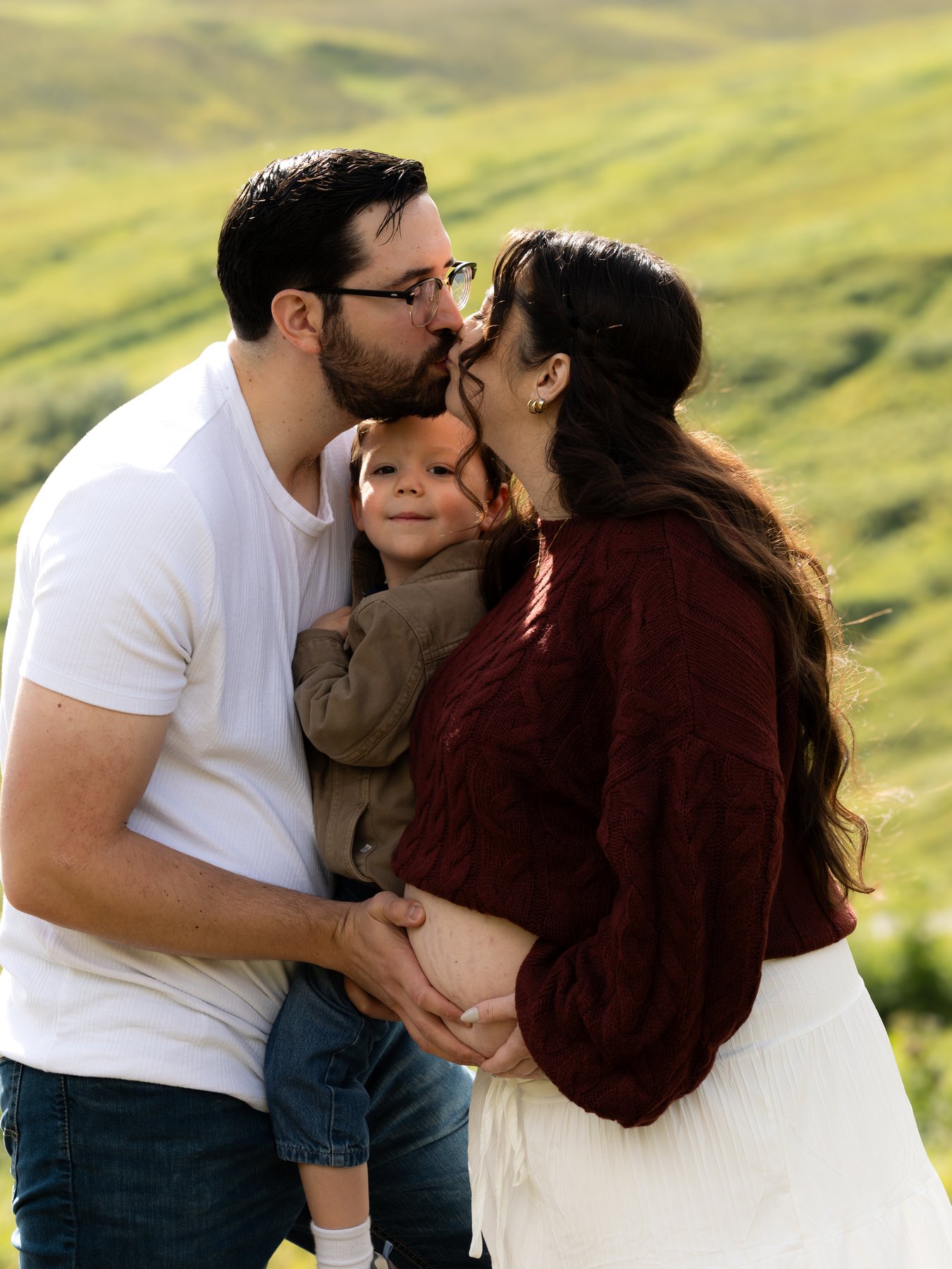 Hannah and Kenny sharing a kiss with their child between them in Alaska