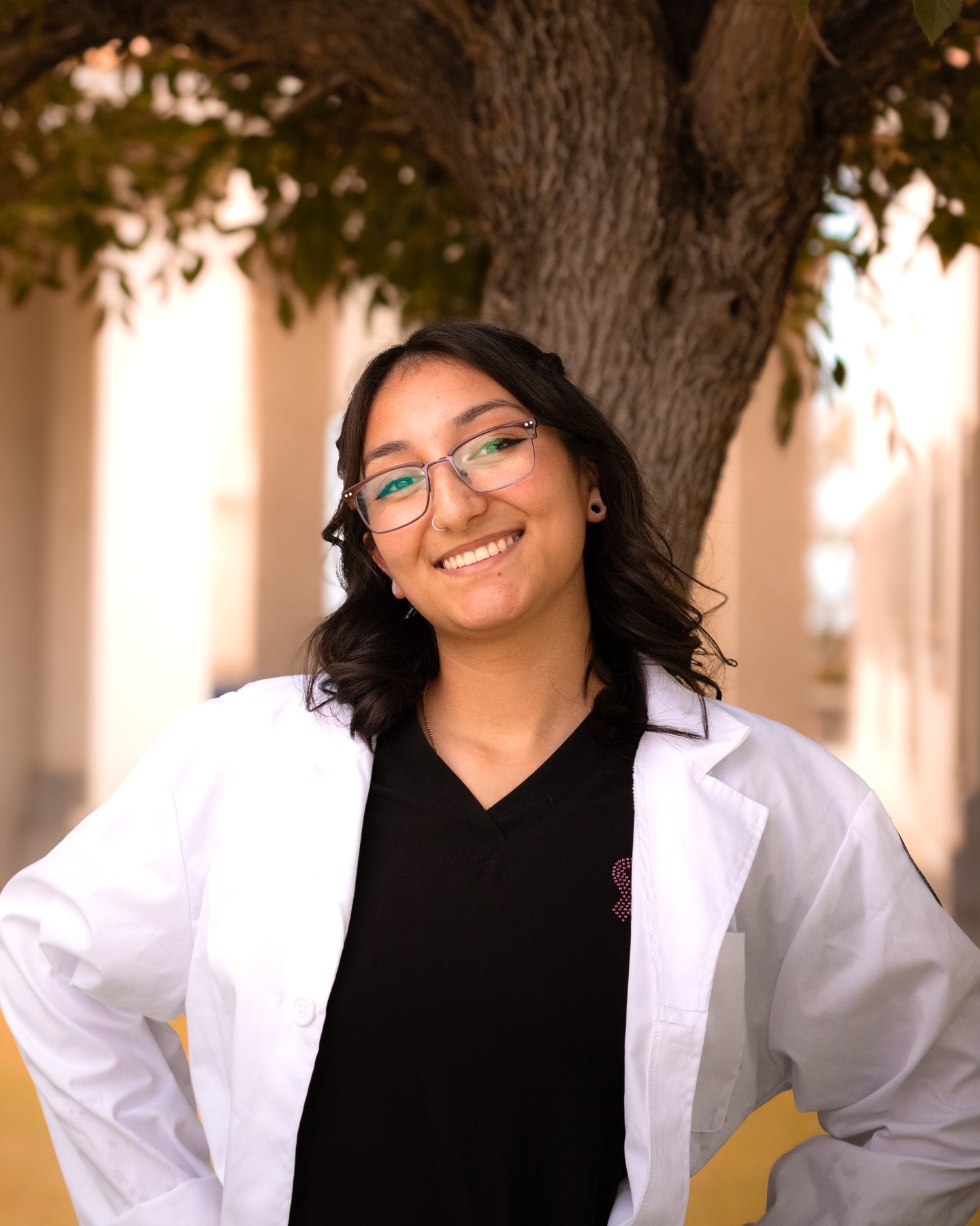 Mia smiling in a white coat during her graduation portraits