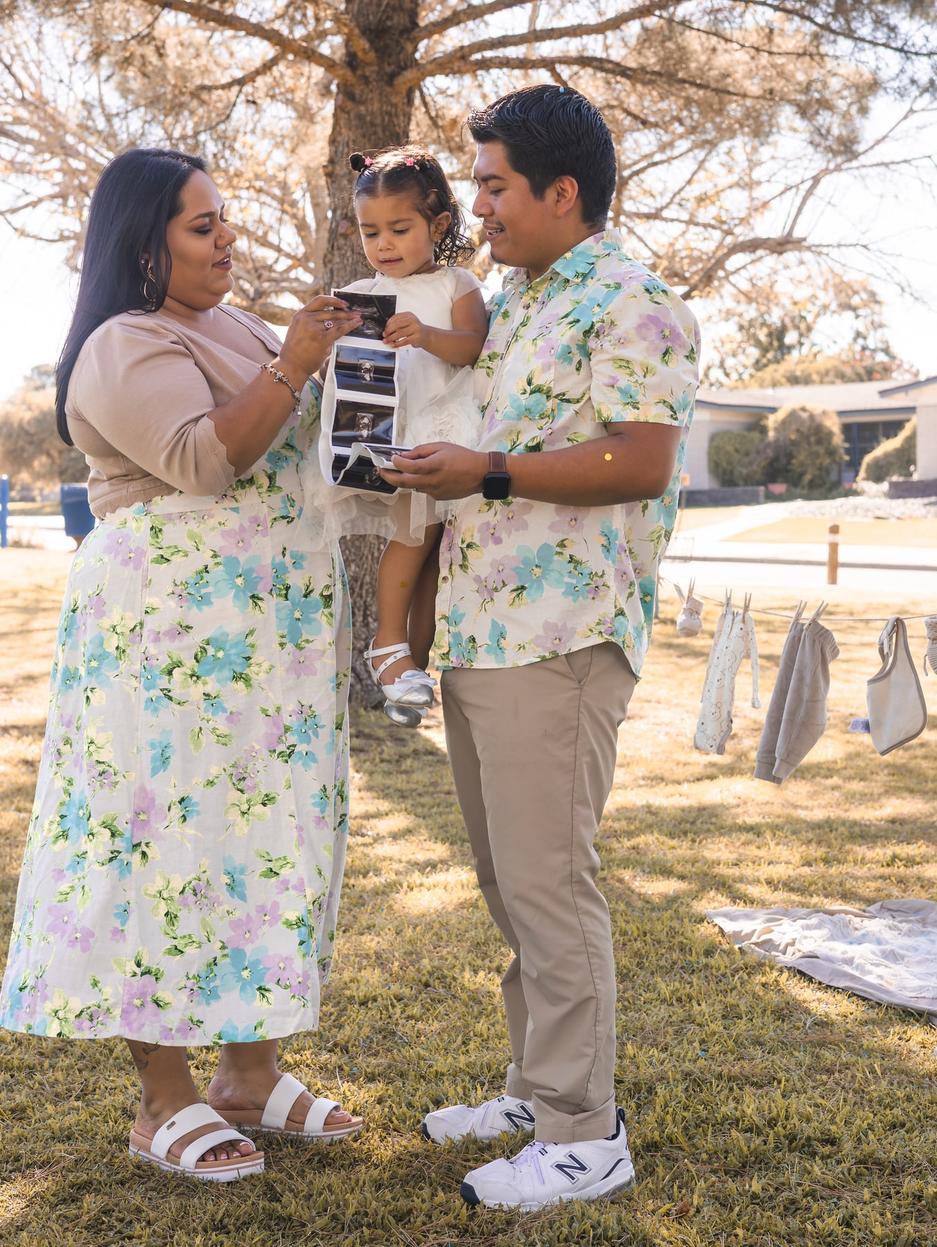 A family standing together and holding a strip of sonogram images
