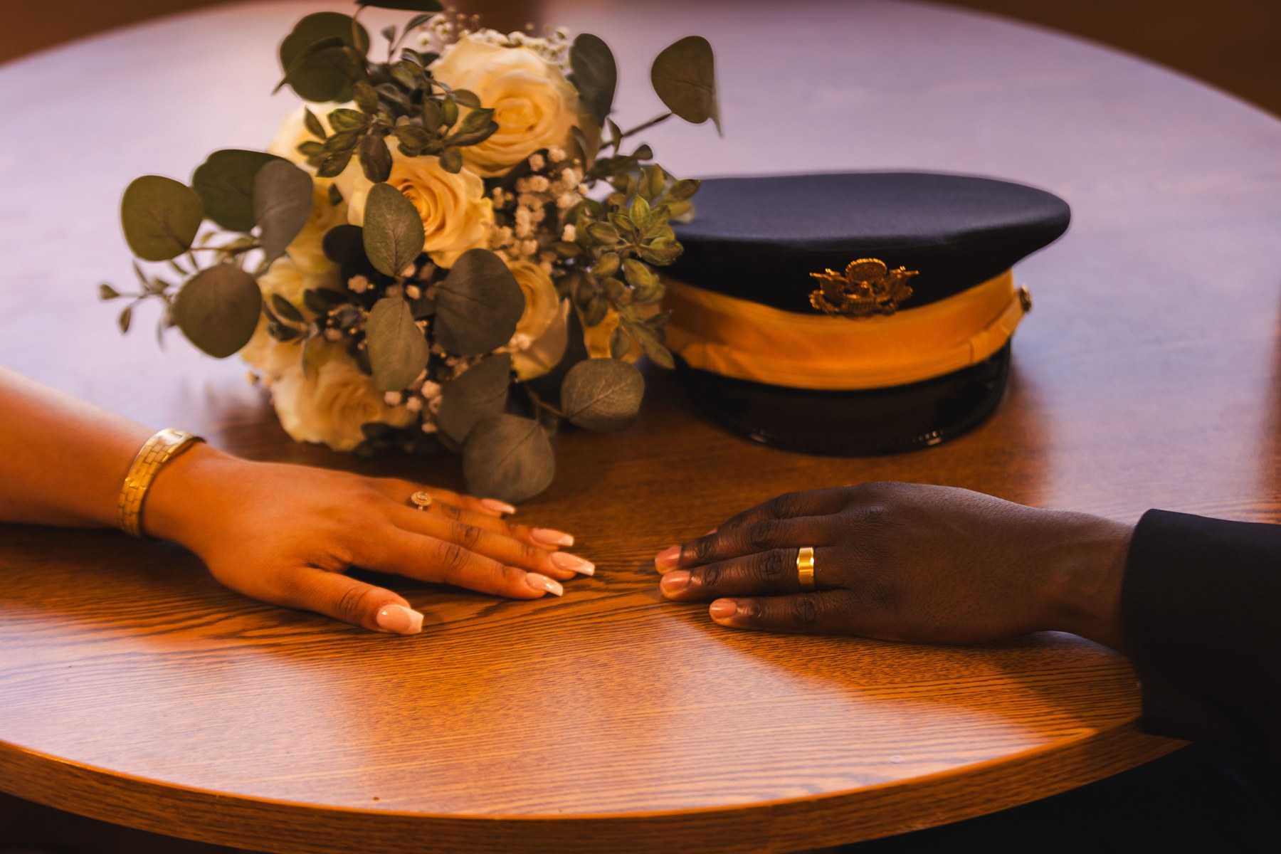 A close view of their hands, rings and bouquet